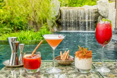 a table with four drinks on it next to a pool at Keemala - Tree Pool House in Kamala Beach