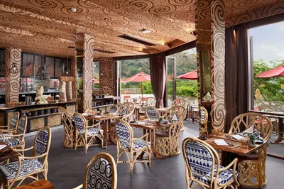 a restaurant with wooden tables and chairs and windows at Keemala - Tree Pool House in Kamala Beach