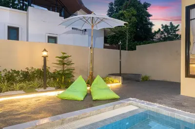 two lime green mats next to a swimming pool with an umbrella at Amaleena Pool Access Suites in Ban Bang Chak