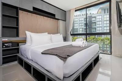 a large bed in a room with a large window at Deluxe 1BR Pool view 58SQM in Kamala Condo Citygate P302 in Kamala Beach
