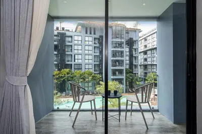a room with a balcony with a table and chairs at Deluxe 1BR Pool view 58SQM in Kamala Condo Citygate P302 in Kamala Beach