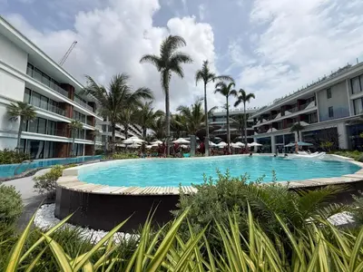 a swimming pool in a resort with palm trees at Sunshine BEACH FRONT in Layan Beach