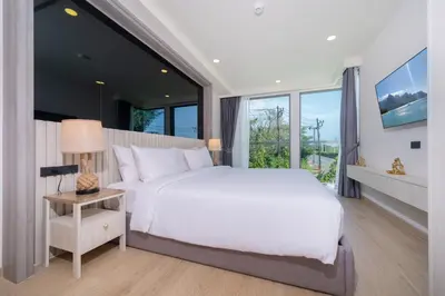 a bedroom with a white bed and a large window at Phuket Family apartment in Phuket Town