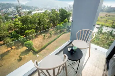 a balcony with two chairs and a table with a view at 1BR Mountain View Condo Citygate P708 in Kamala Beach