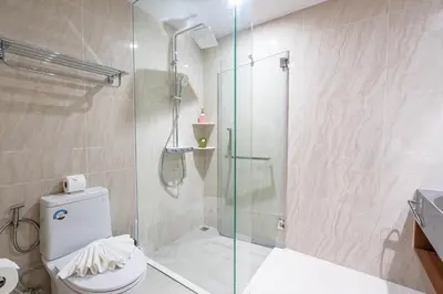 a bathroom with a toilet and a glass shower at Beachside Residences 3 BR apartment by NLA in Bang Tao Beach
