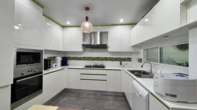 a kitchen with white cabinets and a pendant light at Family House Patong - Homestay in Patong Beach