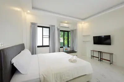 a white bedroom with a bed and a television at Nua Tone Pool Villa I Mountain View I Bangtao Beach in Ban Thalat Choeng Thale