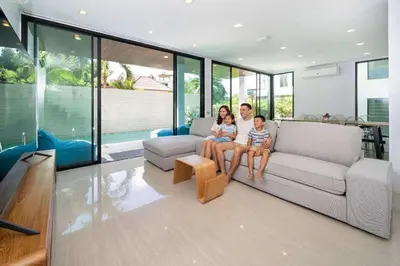 a family sitting on a couch in a living room at 3-Story Pool Villa Near Kata Beach - UTK 4 in Kata Beach