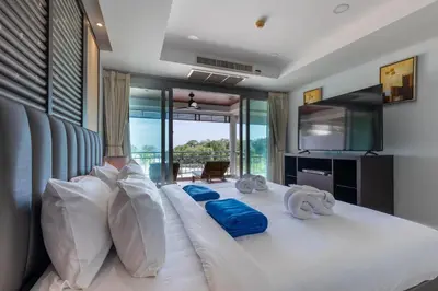 a bedroom with a large white bed with blue pillows at Sea view apartment at Bel Air Panwa in Ban Ao Makham