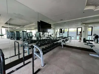 a gym with a large mirror and lots of machines at Elegant Stay with 360 degree Panoramic Rooftop Pool in Ban Sam Kong