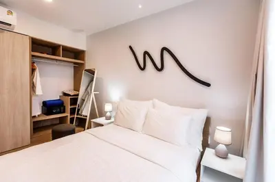 a bedroom with a white bed and a sign on the wall at Sky Park Golg View 2BR Bang Tao Laguna in Laguna Phuket