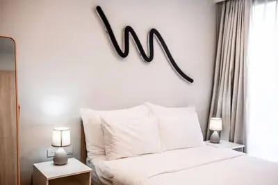 a bedroom with a bed with a w sign on the wall at Sky Park Golg View 2BR Bang Tao Laguna in Laguna Phuket