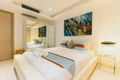 a bedroom with a large white bed with a couch at The Seaview Kata in Kata Beach
