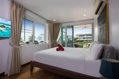 a bedroom with a large white bed with a window at Modern 2BR Condo at Karon Butterfly Phuket in Karon Beach