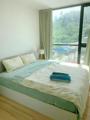 a bedroom with a bed with a large window at The Base Height Phuket in Phuket Town