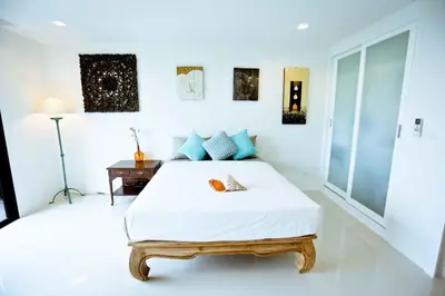 a white bedroom with a bed and a desk at Seaview At Cape Panwa in Panwa Beach