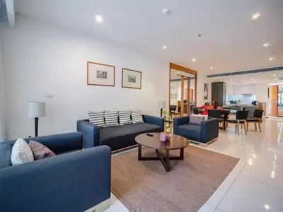 a living room with blue couches and a table at Stylish 2BR Resort Condo with Seaview Surin in Phuket Town