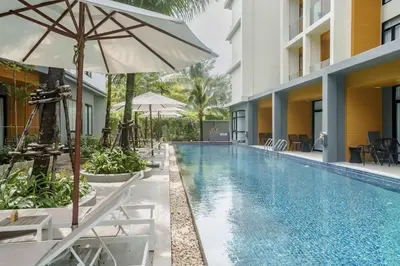 a swimming pool with chairs and an umbrella next to a building at Wyndham 2229 Naiton Beach Studio Forrest View in Phuket Town