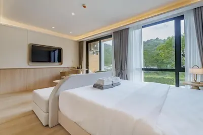 a bedroom with a white bed and a large window at Wyndham Gardens 2413 Elegant Studio Forest View in Phuket Town