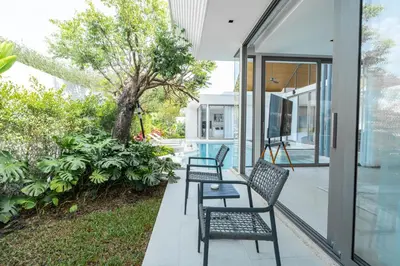 two chairs and a table on the porch of a house at Botanica Aroon Luxury Pool Villa 3 BR Lagoona Bangtao beach in Ban Pak Lak