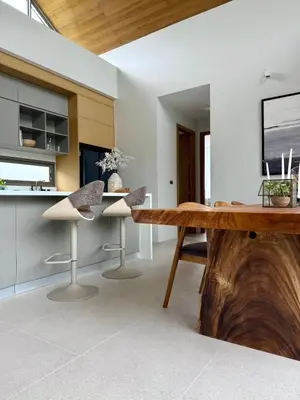 a dining room with a wooden table and stools at Botanica Aroon Luxury Pool Villa 3 BR Lagoona Bangtao beach in Ban Pak Lak