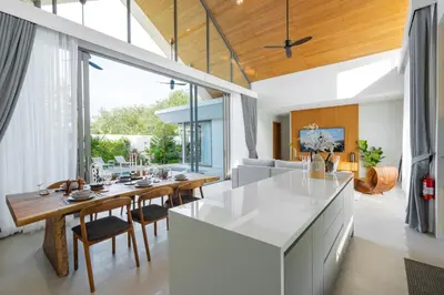 a kitchen and living room with a table and chairs at Botanica Aroon Luxury Pool Villa 3 BR Lagoona Bangtao beach in Ban Pak Lak