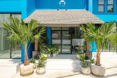 a blue building with palm trees in front of it at Blu Monkey Boutique Naiharn Beach in Nai Harn Beach