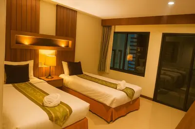 a hotel room with two beds and a window at The Aura Patong in Patong Beach