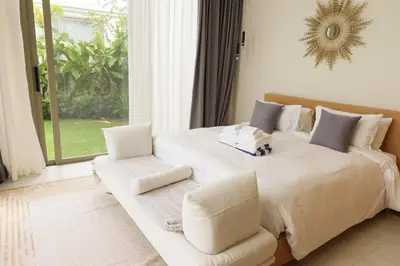 a bedroom with a large white bed with two chairs at Phuket luxury Asherah villa Bang Tao in Ban Phru Champa