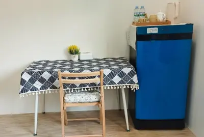 a table with a blue refrigerator next to a table with a chair at Leamsai Whisper Home in Thalang