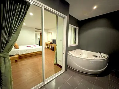 a bathroom with a tub and a bedroom with a bed at Zephyr Suites in Patong Beach