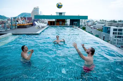 three men playing volleyball in a swimming pool at Zephyr Suites in Patong Beach
