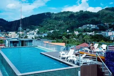 a swimming pool with chairs and a boat on a building at Zephyr Suites in Patong Beach