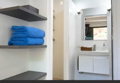 a bathroom with blue towels on a shelf next to a sink at Brickotel Naithon Beach in Nai Thon Beach
