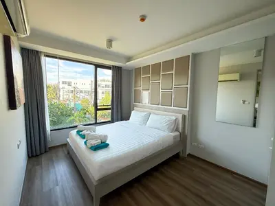 a bedroom with a white bed with a large window at 6th Avenue 2 bedroom in Surin Beach