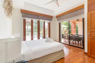 a bedroom with a white bed and a dining room at Spacious Villa with Pool, Garden & Club facilities in Layan Beach