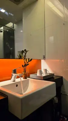 a bathroom with a white sink and an orange wall at Beautiful Pool View Studio in Kata in Kata Beach