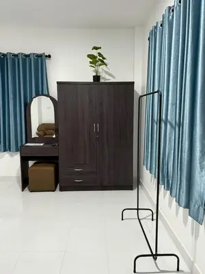 a bathroom with a vanity and a mirror and blue curtains at AN Airport Guesthouse in Nai Yang Beach