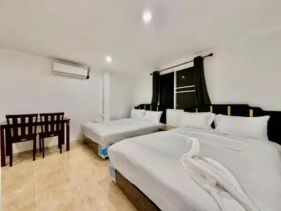 a bedroom with two beds and a table and a chair at Jasmine Residence in Patong Beach