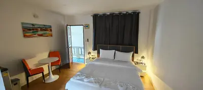 a bedroom with a bed and a table and a window at Tiger Nanai guest house in Patong Beach