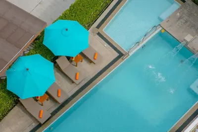 an overhead view of a swimming pool with blue umbrellas and chairs next to at Recenta Suite Phuket Suanluang in Phuket Town