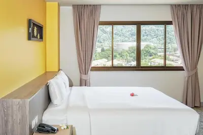 a hotel room with a white bed and a window at Recenta Suite Phuket Suanluang in Phuket Town