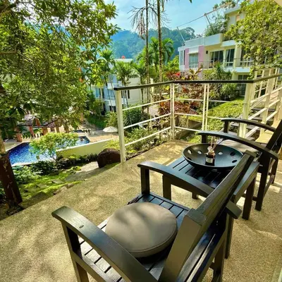 a table and chairs on a patio with a pool at Kamala Hills Ocean Breeze 3 Bedroom Loft with Access to 3 Pools in Kamala Beach