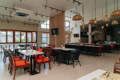 a restaurant with tables and chairs and a tv at Rawayana West Villas & Kids Park in Rawai Beach