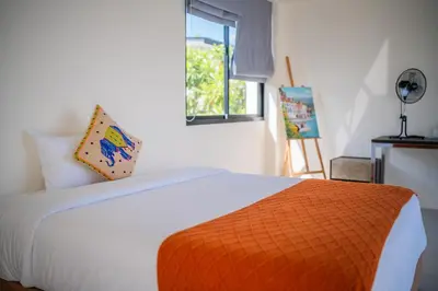 a bedroom with a white bed with an orange pillow at Laguna park 5bedroom private pool villa in Laguna Phuket