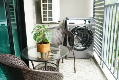 a table and chairs on a balcony with a washing machine at Title - Comfortable 1BR Tropical Retreat in Nai Yang Beach