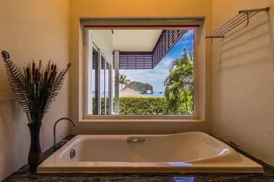 a large bath tub in a room with a window at Sunset bay view villa krabi in Ban Khao Thong