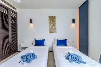 two beds in a room with blue pillows on them at C254 Condo 2BR Pool View Short Walk to Beach in Thalang
