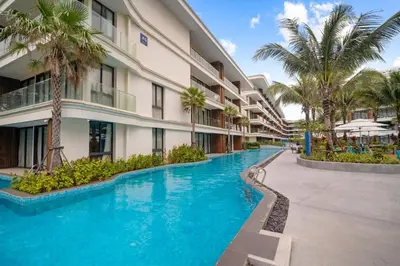 a swimming pool in front of a building with palm trees at Kora Resort A110 – Luxury Beachfront Studio in Phuket Town
