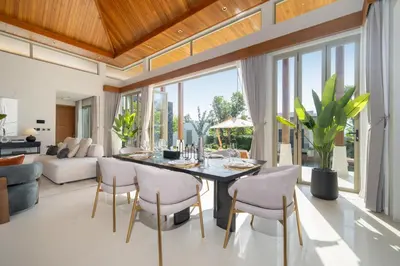 a living room with a dining room table and chairs at Luxury Royale Bangtao Pool Villa with maid in Thalang